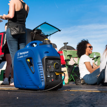 Westinghouse | iGen2200c inverter generator sitting on the ground with people tailgating in the background
