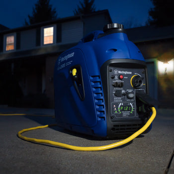 Westinghouse | iGen2500 inverter generator sitting on driveway in the dark. House with lights on in the background.
